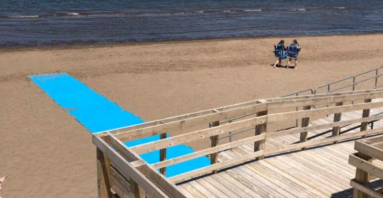 La rampe d'accès à la plage avec tapis sur le sable pour accéder à l'eau