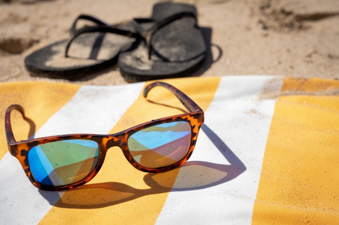 Serviette de plage étendue sur le sable avec des lunettes de soleil par-dessus